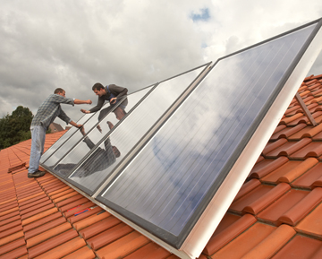 Zwei Monteure bringen eine Solaranlage auf einem Dach an