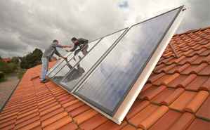 Zwei Männer installieren eine Solaranlage auf einem Dach
